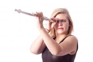 Young blond woman and flute against white background in studio